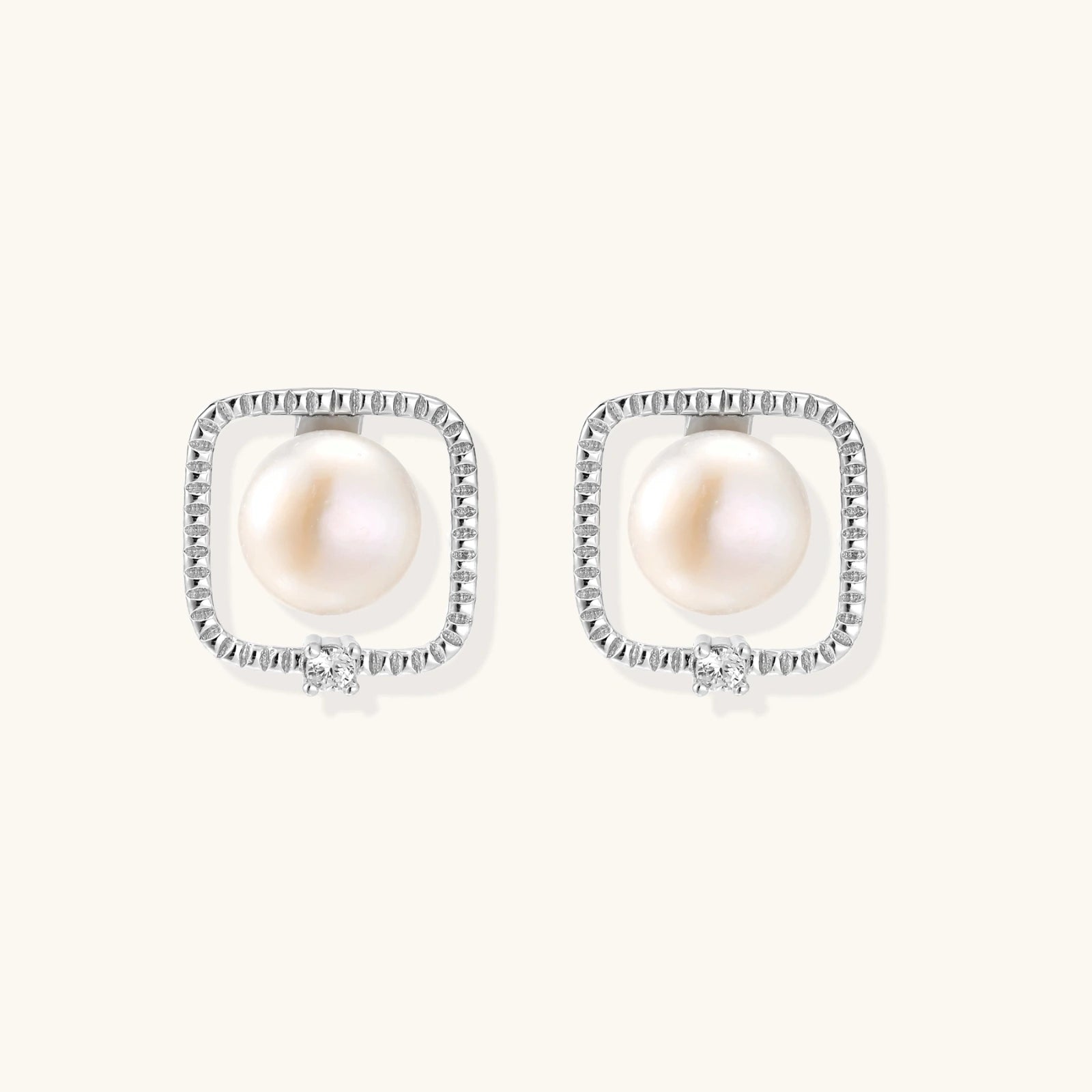 Rhodium-plated silver stud earrings with cushion frame, centered freshwater pearl, and tiny crystal accent