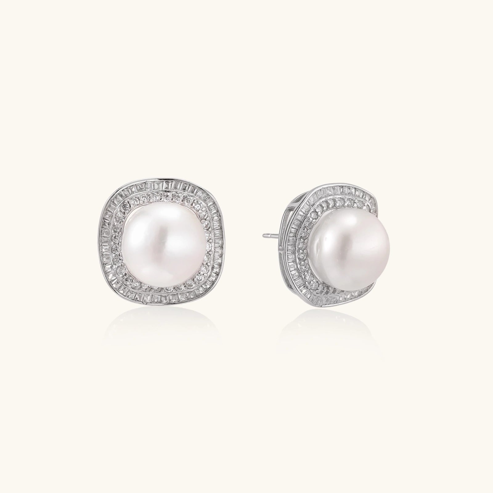 Rhodium-plated sterling silver stud earrings with round freshwater pearls surrounded by geometric crystal halos on cream background.