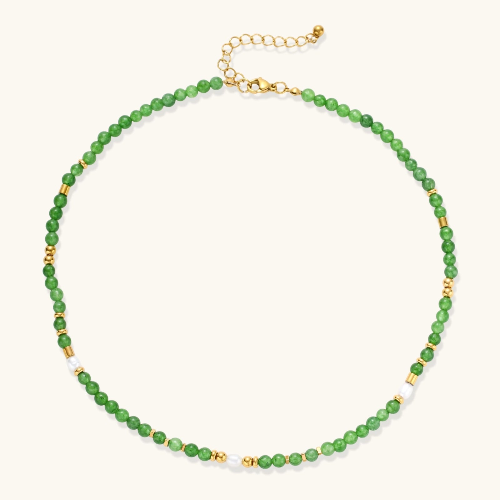 Layered necklace with green stone beads, gold spacers, white accents, and protective eye pendant on cream background.